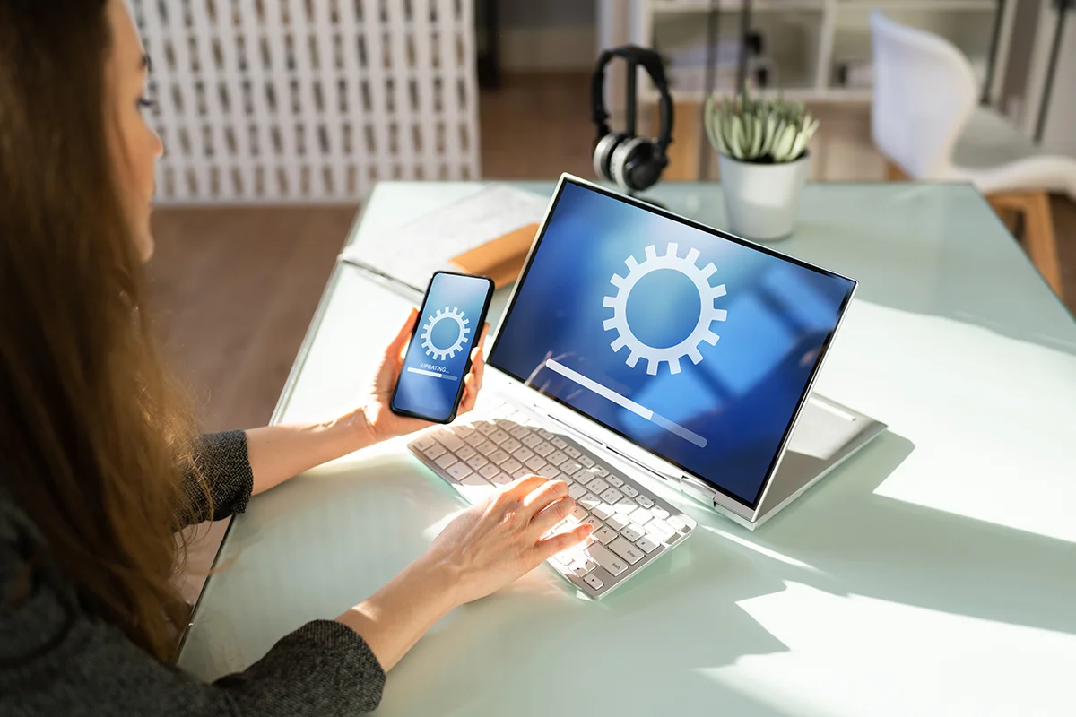 An employee sits at a desk in a sunny office, waiting for a computer to load due to network issues, showing the concept of IT pain points for small businesses