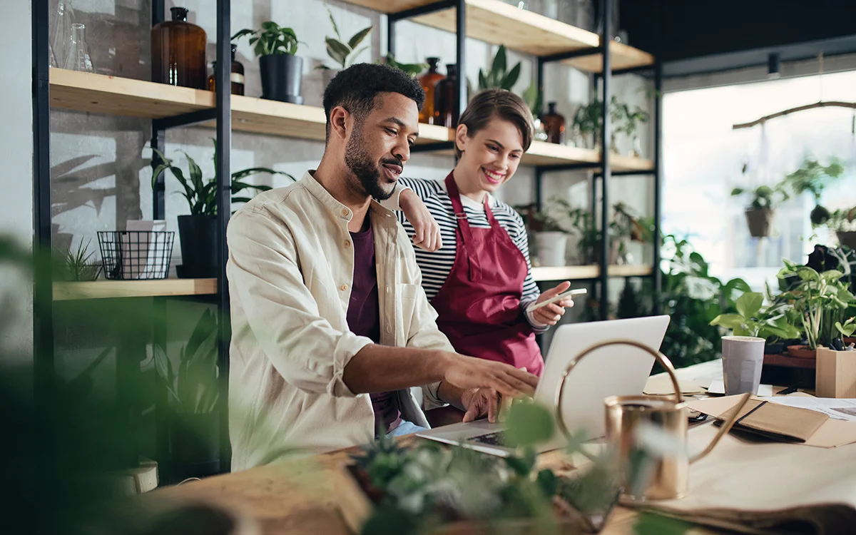 Small business employees at a plant shop point to a computer, showing the concept of strategic IT planning